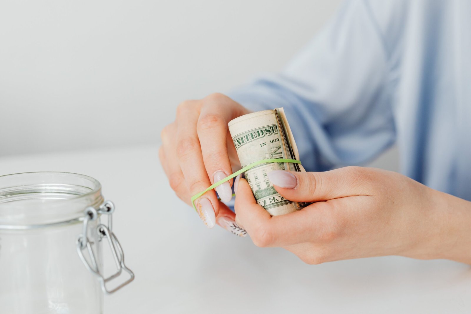 Hands rolling up cash to set aside in a savings jar as part of an emergency fund