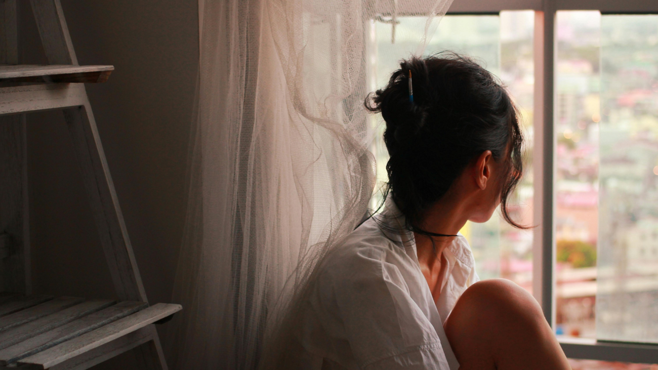 Woman sitting quietly by a sunlit window, taking a calm morning pause to reduce stress and anxiety naturally