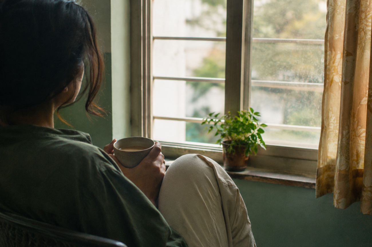 Person sitting quietly by a window holding a cup of chai, reflecting on how to set boundaries without guilt