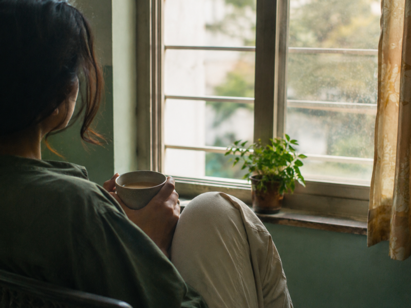 Person sitting quietly by a window holding a cup of chai, reflecting on how to set boundaries without guilt