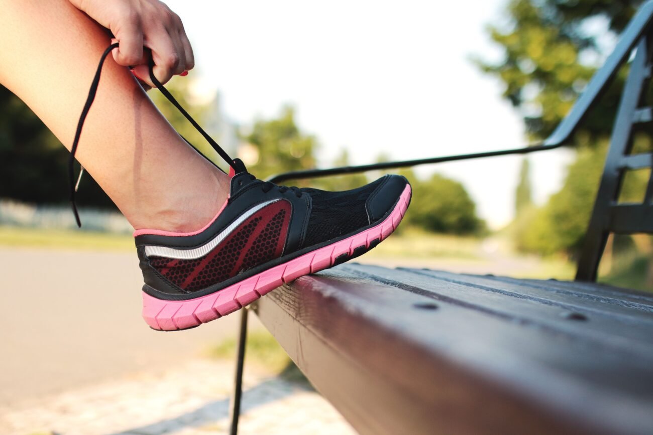 Person lacing up sneakers by the door in the morning, a simple first step toward learning how to start exercising