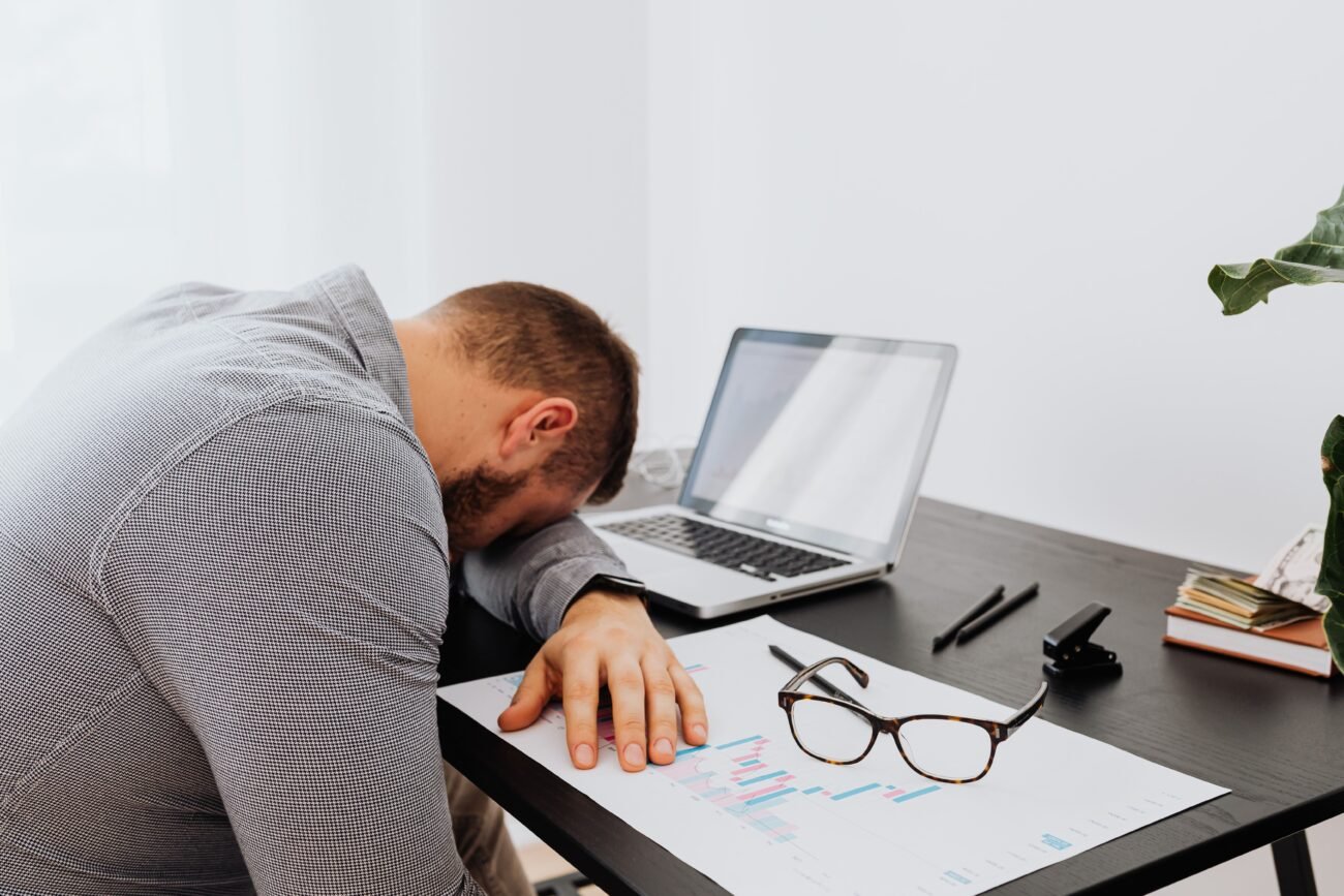 A tired professional resting their head in their hands, showing early burnout symptoms