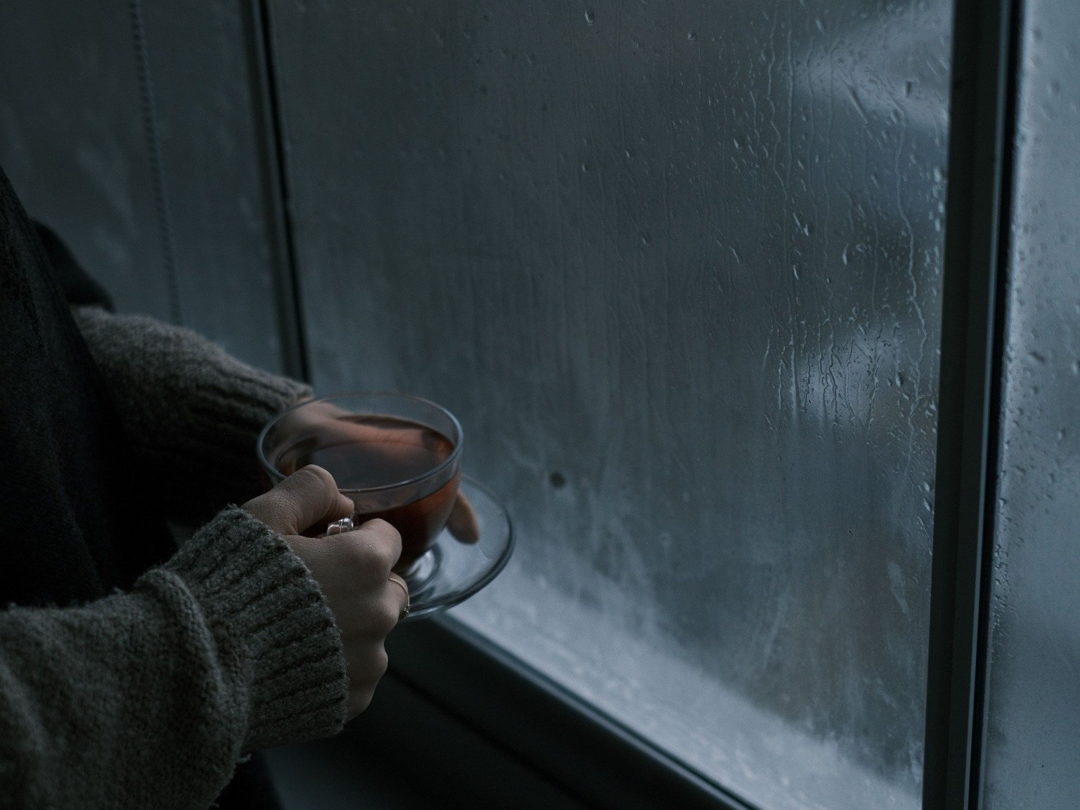 A warm cup of tea by a rain-covered window, capturing a cozy monsoon travel moment