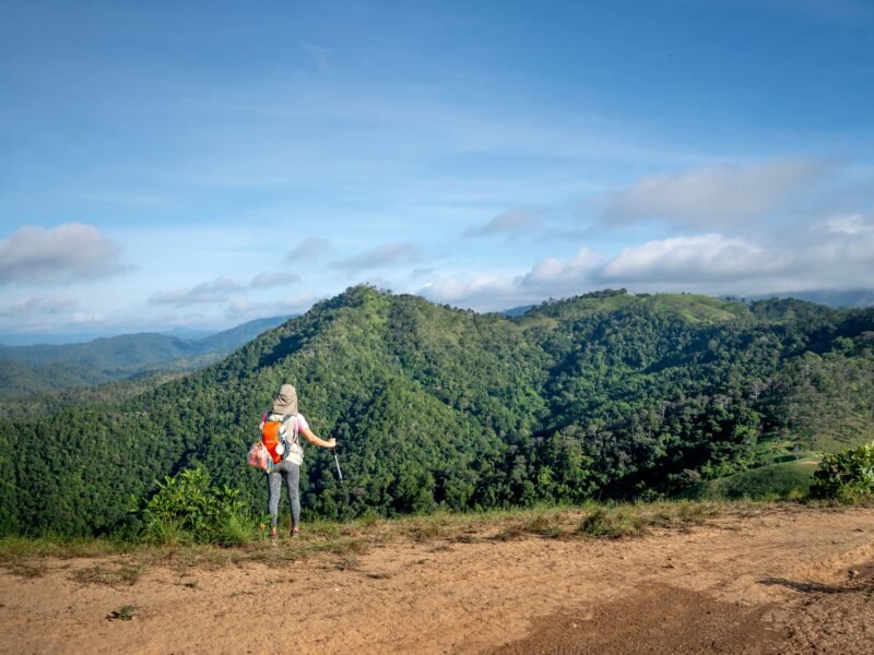 A traveler with a backpack standing at a scenic viewpoint, reflecting mindful and meaningful travel