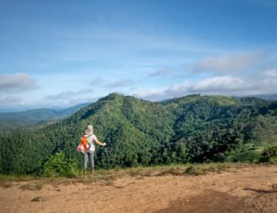 A traveler with a backpack standing at a scenic viewpoint, reflecting mindful and meaningful travel