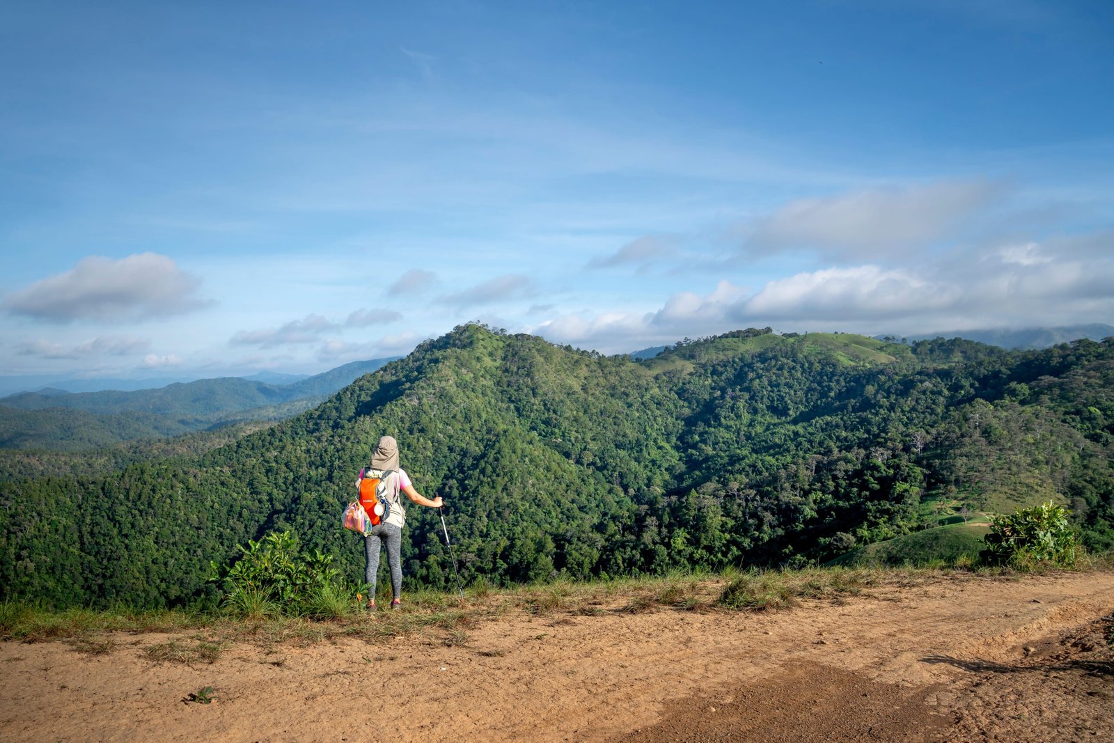 A traveler with a backpack standing at a scenic viewpoint, reflecting mindful and meaningful travel