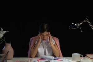 A person rubbing their temples, illustrating physical burnout symptoms like headaches and tension